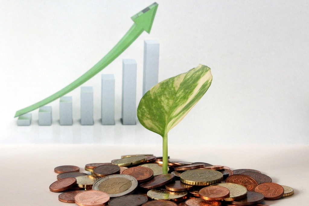 A young plant growing out of a pile of coins, symbolizing dividends reinvested and compounding over time