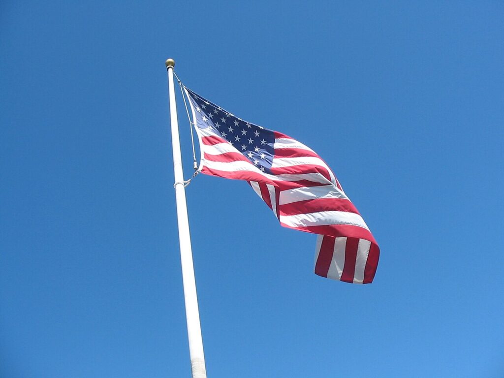 An American flag waving in the wind on a flagpole against the sky